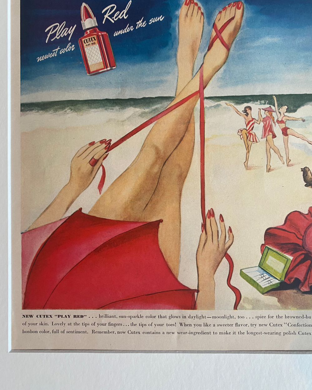 Close-up detail of an original 1946 Cutex Play Red advertisement featuring red nail polish and a vintage beach illustration