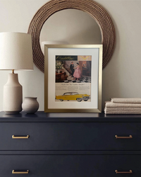 Original Cadillac vintage advertisement featuring a yellow Cadillac, beautifully framed in brushed brass and styled on a dark dresser with neutral accessories.
