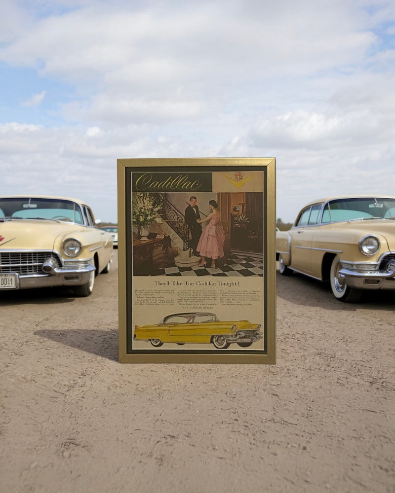Original 1950s Cadillac magazine advertisement framed in gold, featuring an elegant couple and classic yellow Cadillac