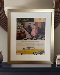 Original Cadillac “They’ll Take the Cadillac Tonight” vintage advertisement in a brushed brass frame with an off-white mat, styled on a dark dresser.