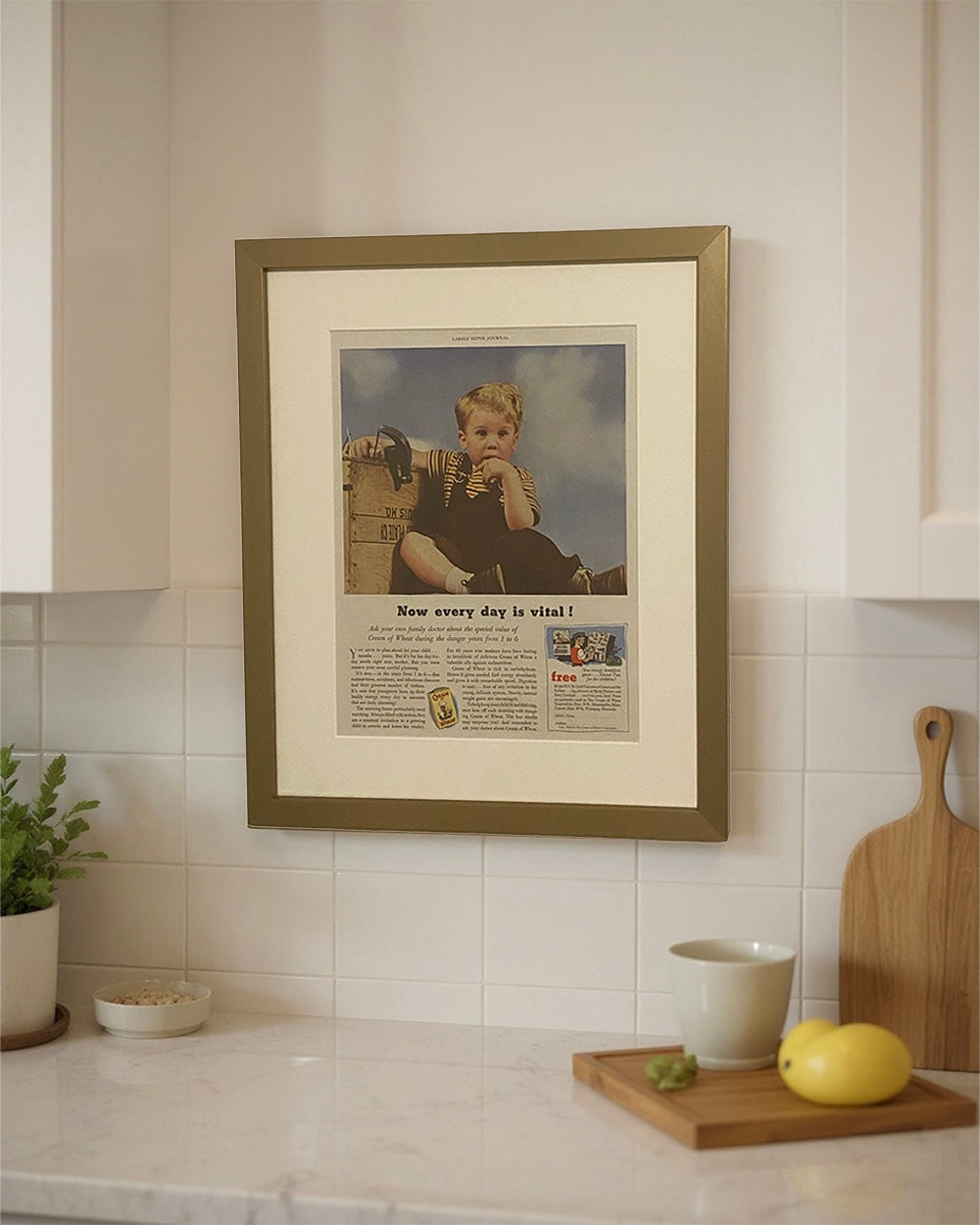 Framed 1953 Cream of Wheat vintage advertisement styled on a kitchen wall above a countertop in a bright transitional kitchen.