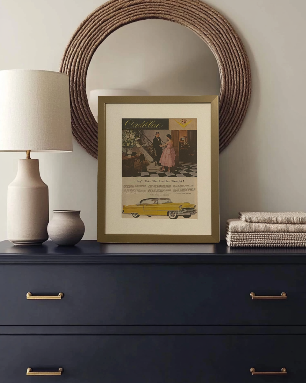 Original 1955 Cadillac vintage advertisement displayed in a thin brass frame on a bedroom dresser with warm modern décor.