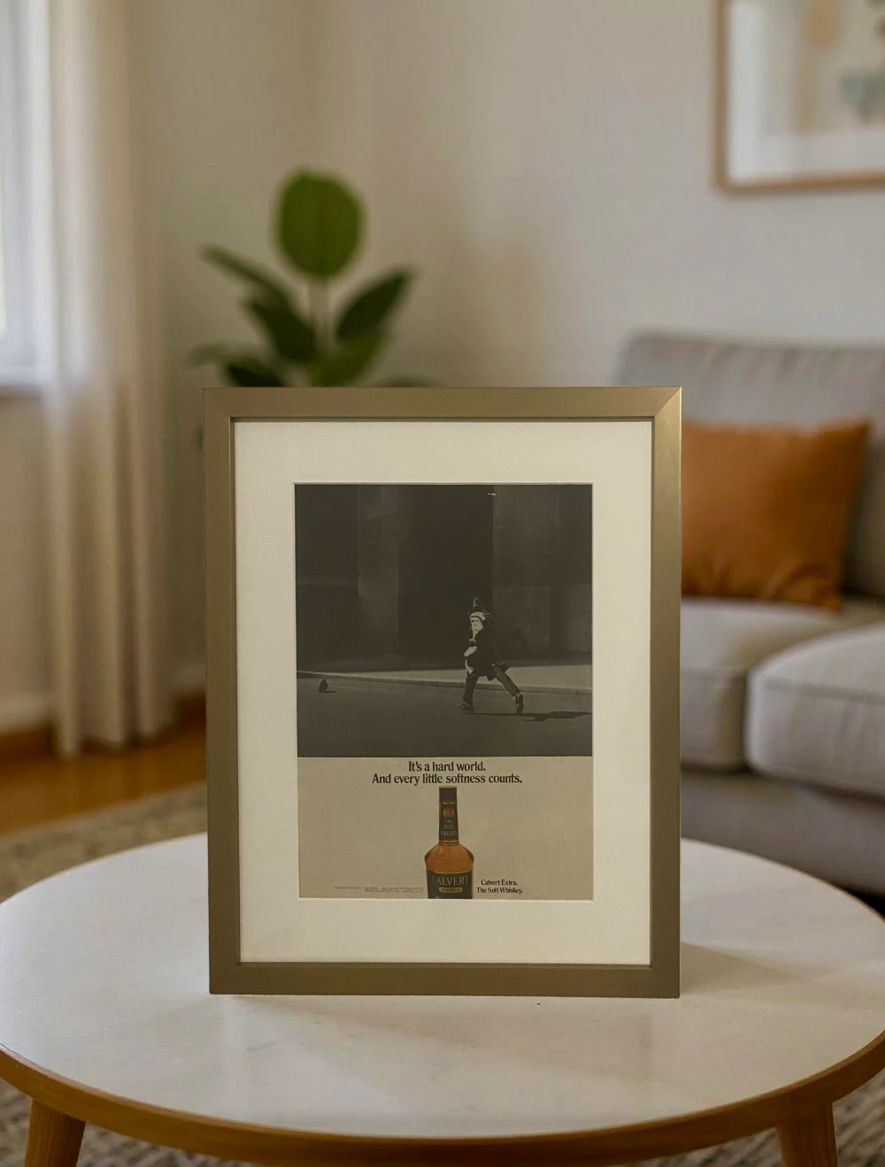 Original Calvert Extra “The Soft Whiskey” vintage advertisement in a thin brass frame displayed on a modern coffee table.