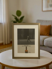 Original Calvert Extra “The Soft Whiskey” vintage advertisement in a thin brass frame displayed on a modern coffee table.