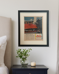 Framed original vintage Avis automotive advertisement styled above a nightstand in a warm neutral bedroom