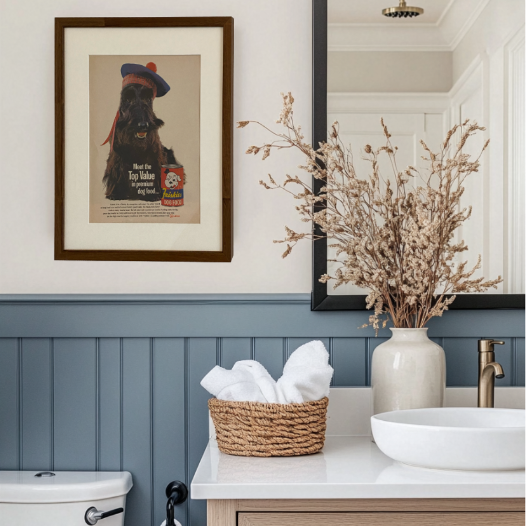 Original vintage Friskies dog food advertisement beautifully framed in brown with an off-white mat, styled in a blue and white bathroom.