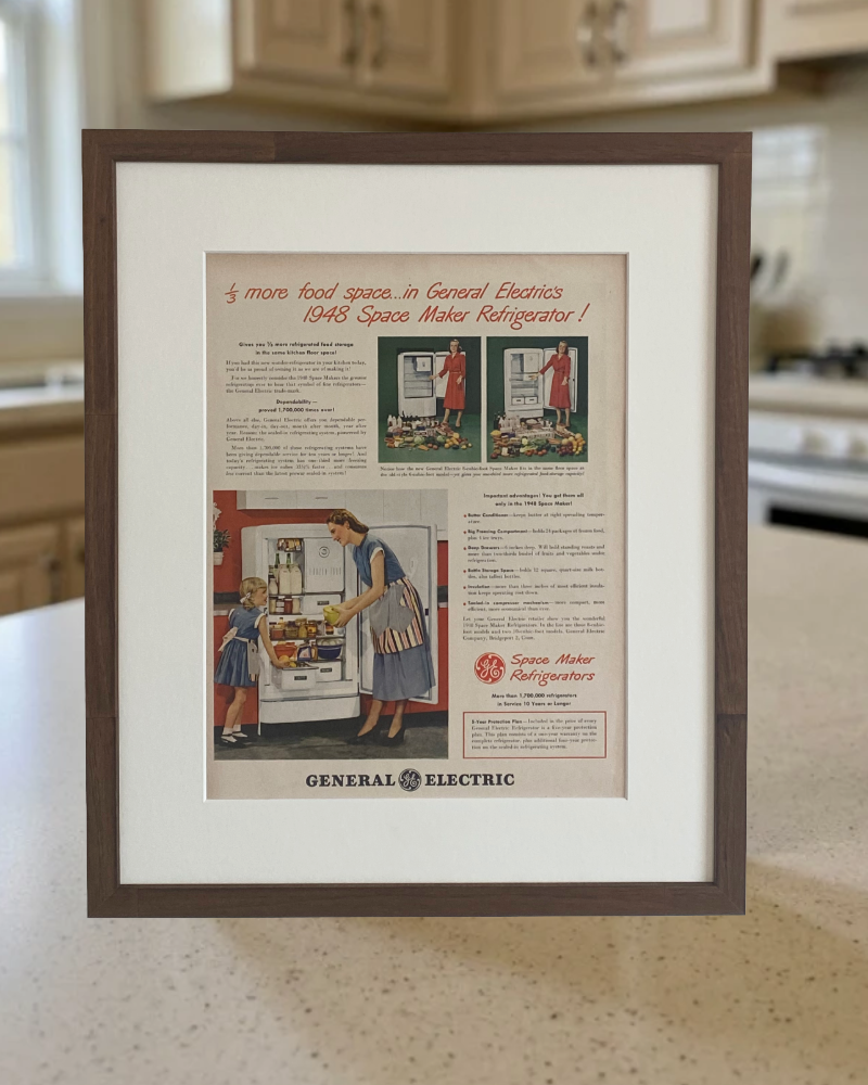 Original 1948 General Electric Space Maker Refrigerator vintage advertisement in a handcrafted walnut frame displayed on a kitchen countertop.