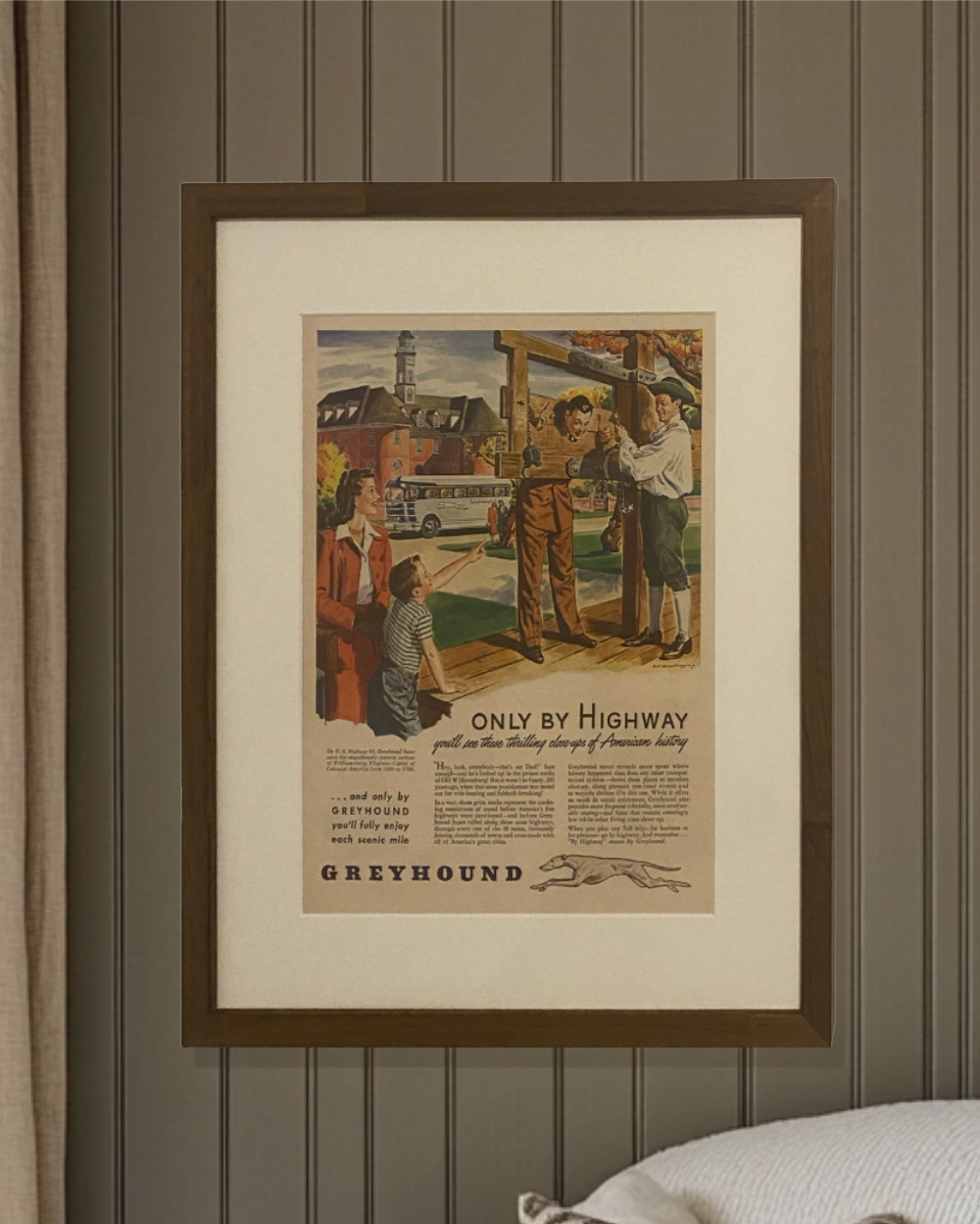 Original 1940s Greyhound “Only by Highway” magazine advertisement in a walnut brown frame displayed against a paneled wall.