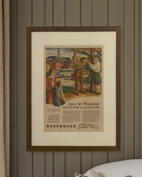 Original 1940s Greyhound “Only by Highway” magazine advertisement in a walnut brown frame displayed against a paneled wall.