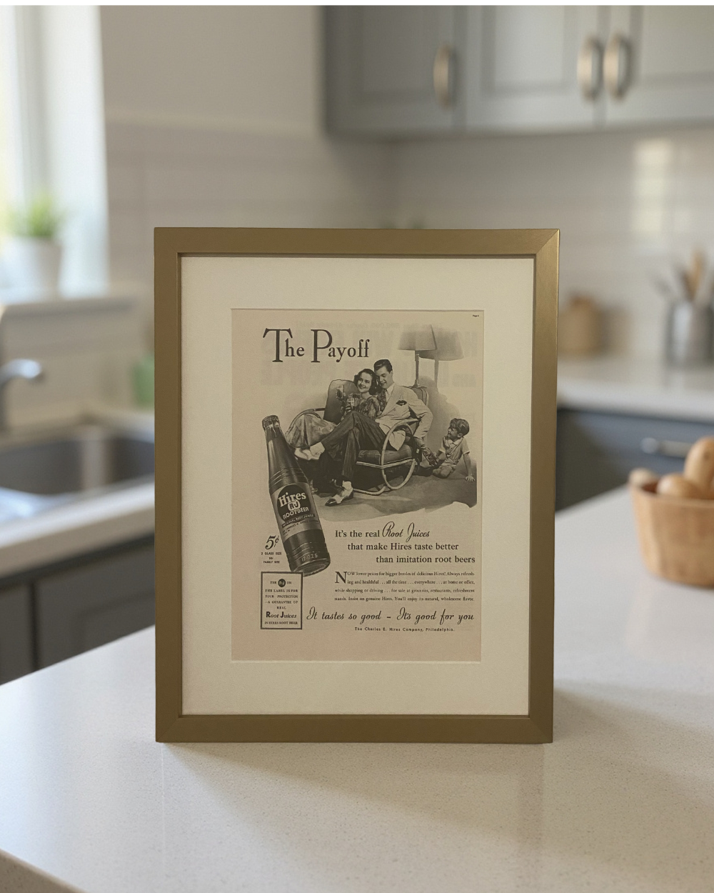 Original 1941 Hires Root Beer advertisement in a brass frame displayed on a kitchen countertop with a soft neutral kitchen background