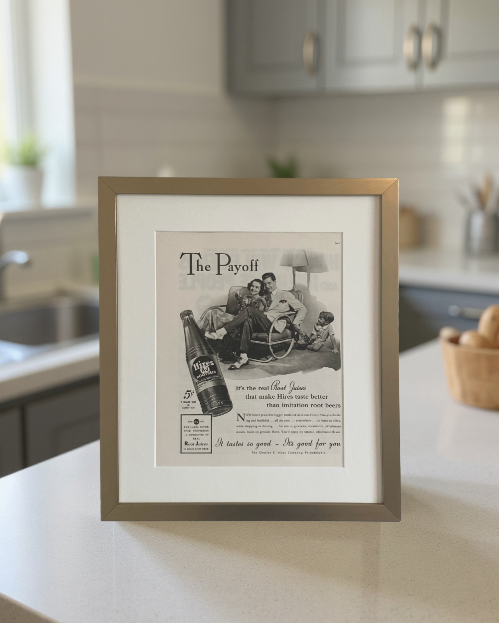 Original Hires Root Beer “The Payoff” vintage advertisement in a brushed brass frame with an off-white mat, styled in a bright modern kitchen.