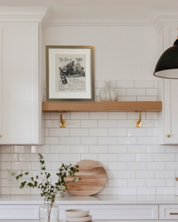 Original Hires Root Beer “The Payoff” vintage advertisement in a brushed brass frame styled on a floating shelf in a modern kitchen.