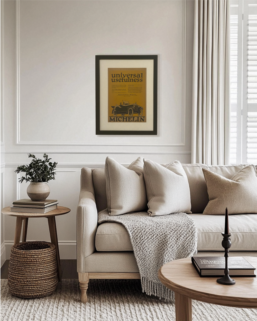 Original Michelin “Universal Usefulness” magazine advertisement displayed in a black frame above a neutral living room sofa in a warm transitional interior.