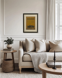 Original Michelin “Universal Usefulness” magazine advertisement displayed in a black frame above a neutral living room sofa in a warm transitional interior.