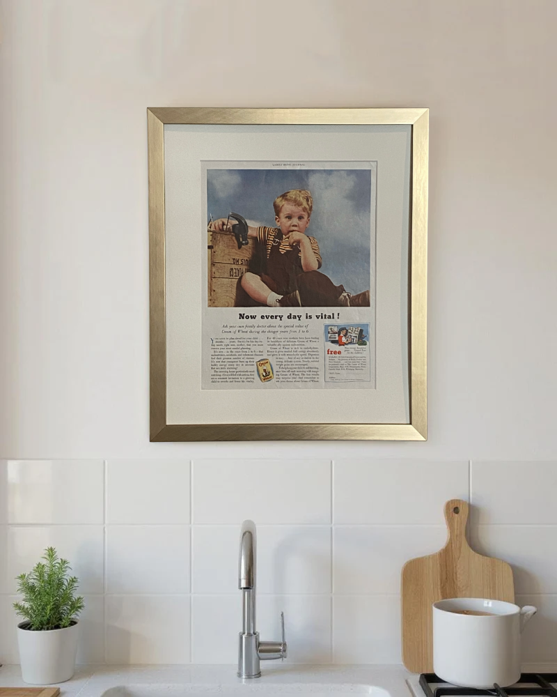 Original vintage Cream of Wheat advertisement beautifully framed in brushed brass and displayed above the counter in a modern kitchen.