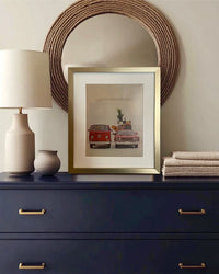 Original vintage Volkswagen advertisement beautifully framed in brushed brass and styled on a dark dresser with warm neutral decor.