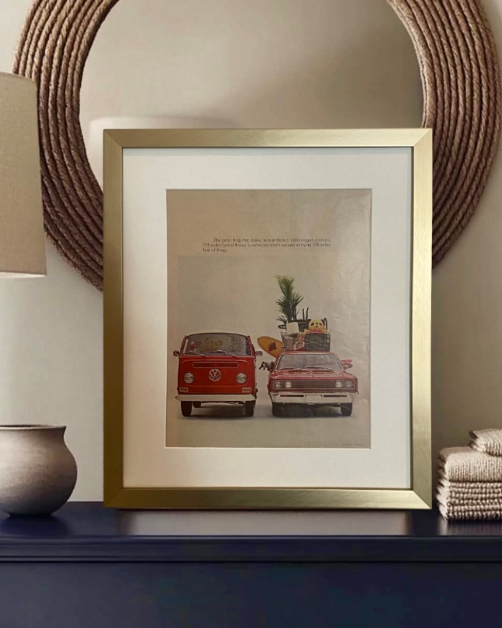 Original vintage Volkswagen advertisement featuring a red VW bus and station wagon, beautifully framed in brushed brass with an off-white mat.