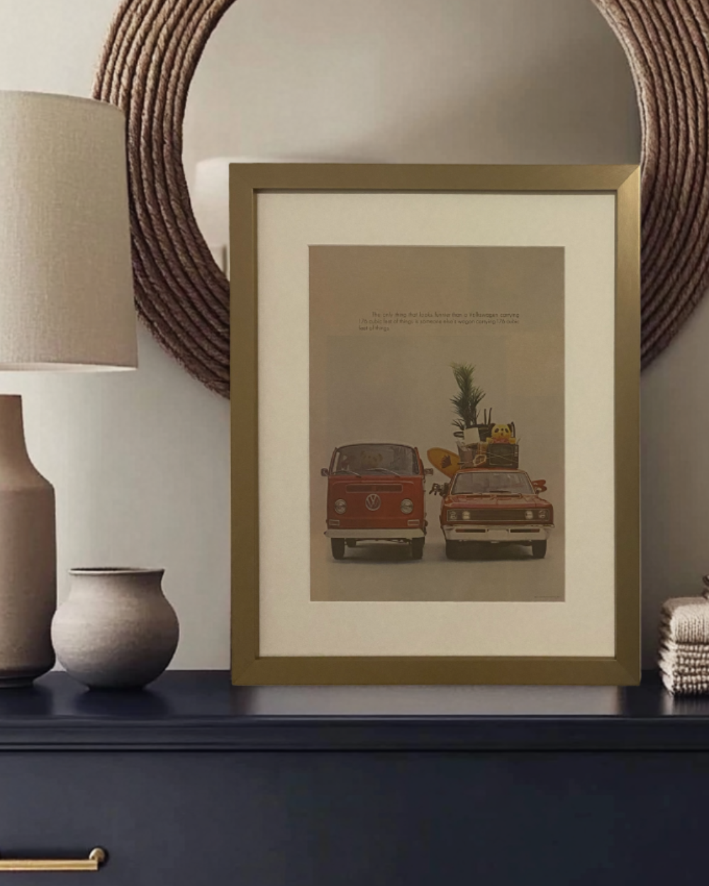 Original vintage Volkswagen “176 Cubic Feet” magazine advertisement professionally framed with an off-white archival mat, styled on a modern dresser with a brass frame.
